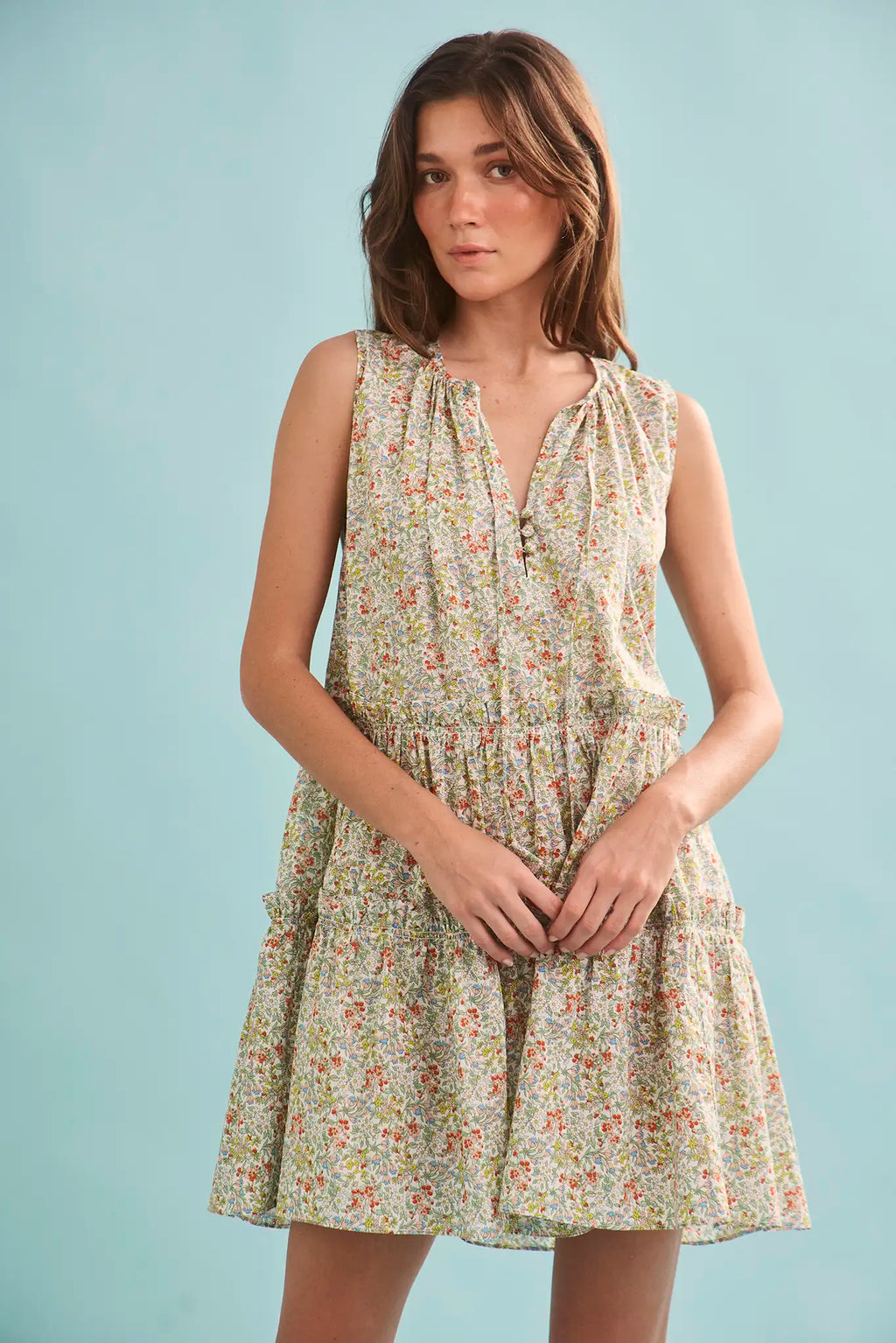 The Fawn Dress in Coral Multi paired with pale yellow shoes on a blue background.