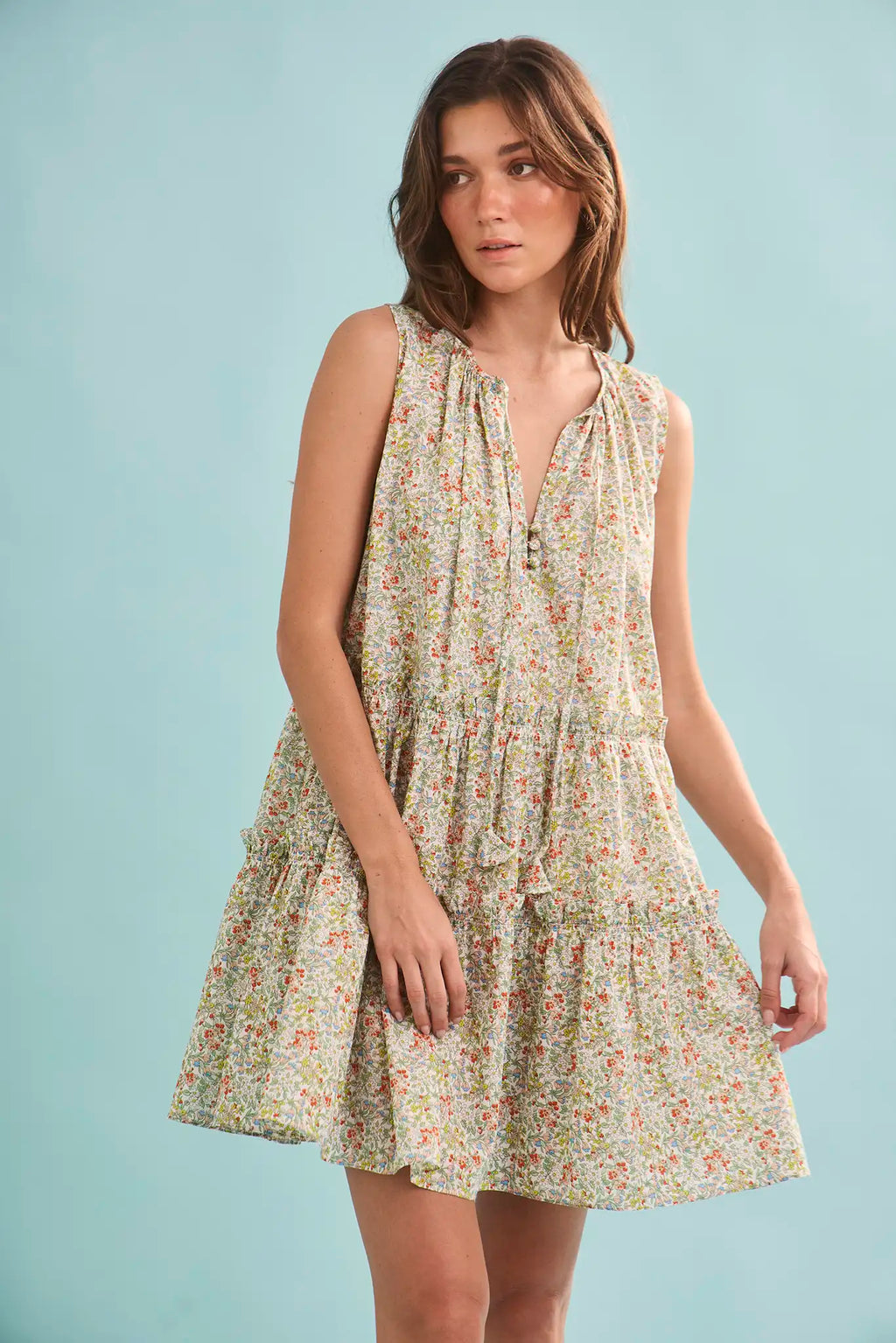 The Fawn Dress in Coral Multi paired with pale yellow shoes on a blue background.