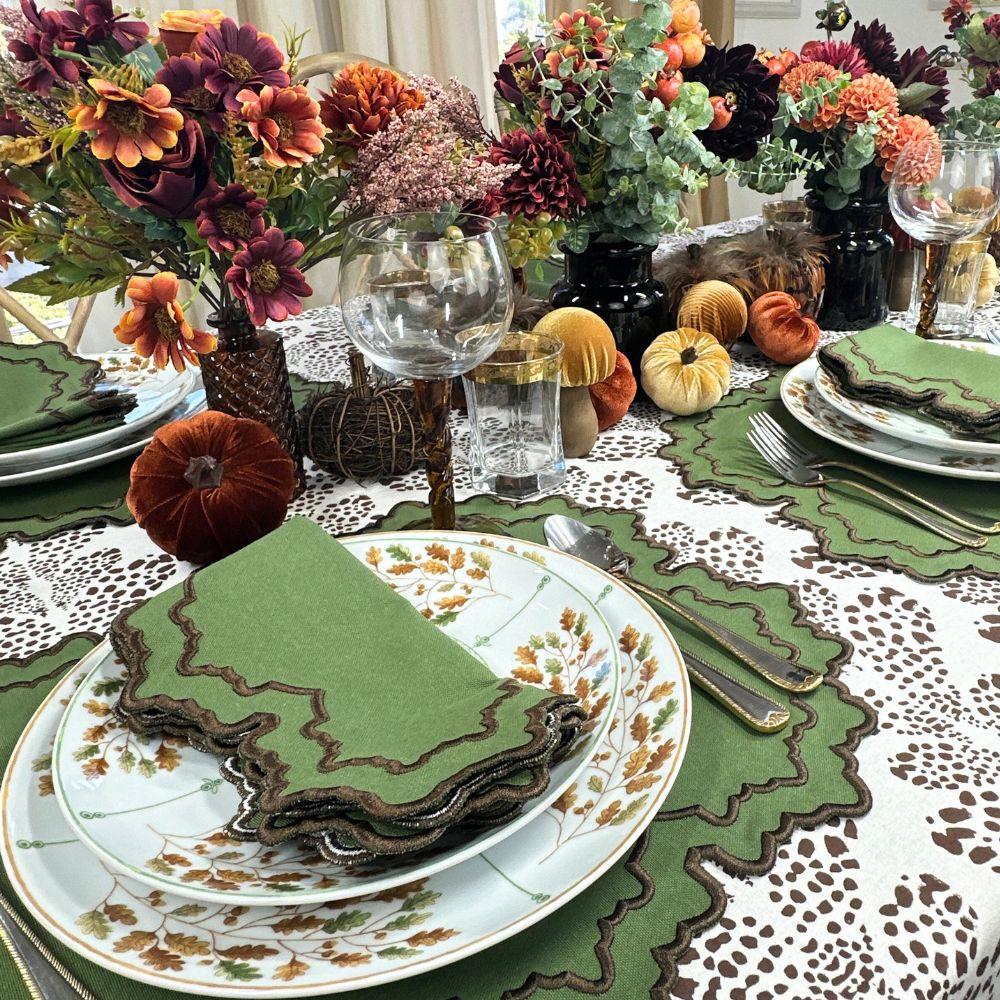 Decorative table setting with fall-themed elements including pumpkins and floral arrangements. Thanksgiving table, embroidered placemats.