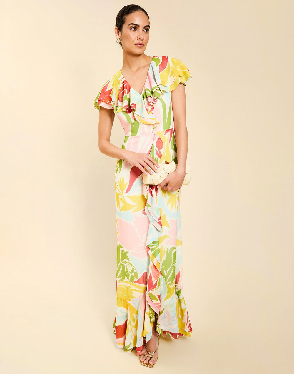 Woman wearing the Mestiza Fernanda Gown in Autumn Daydreaming print, featuring a V-neckline, cascading ruffle details, cap-style ruffle sleeves, fitted bodice, and flowing chiffon skirt.