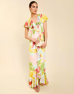 Woman wearing the Mestiza Fernanda Gown in Autumn Daydreaming print, featuring a V-neckline, cascading ruffle details, cap-style ruffle sleeves, fitted bodice, and flowing chiffon skirt.