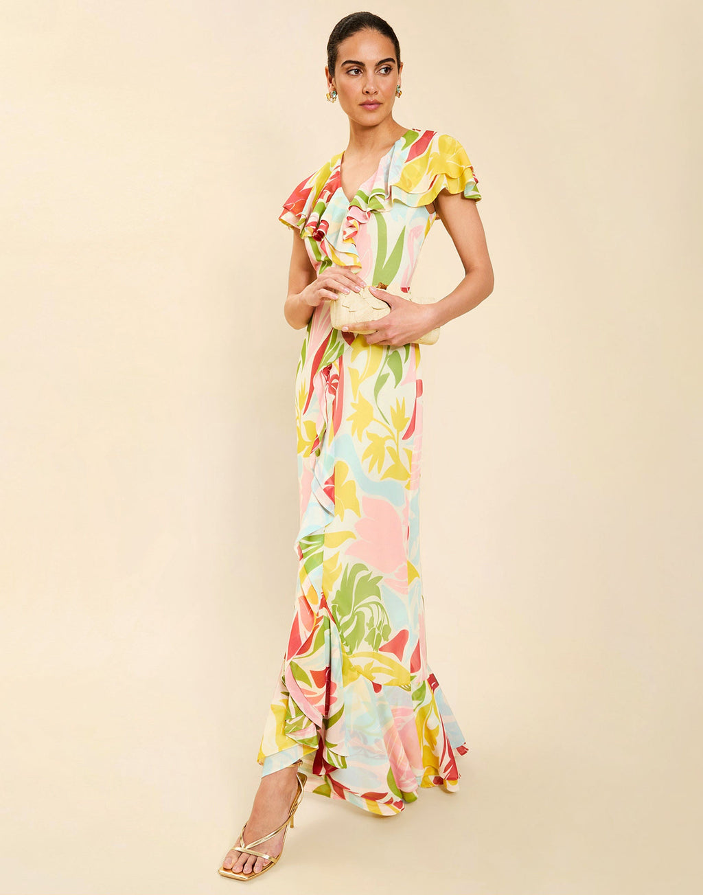 Woman wearing the Mestiza Fernanda Gown in Autumn Daydreaming print, featuring a V-neckline, cascading ruffle details, cap-style ruffle sleeves, fitted bodice, and flowing chiffon skirt.