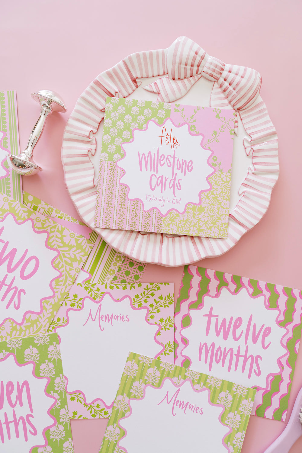 Top-down view of Precious Pinks milestone cards showing pink and green patterned cards and boxed set on striped bow plate