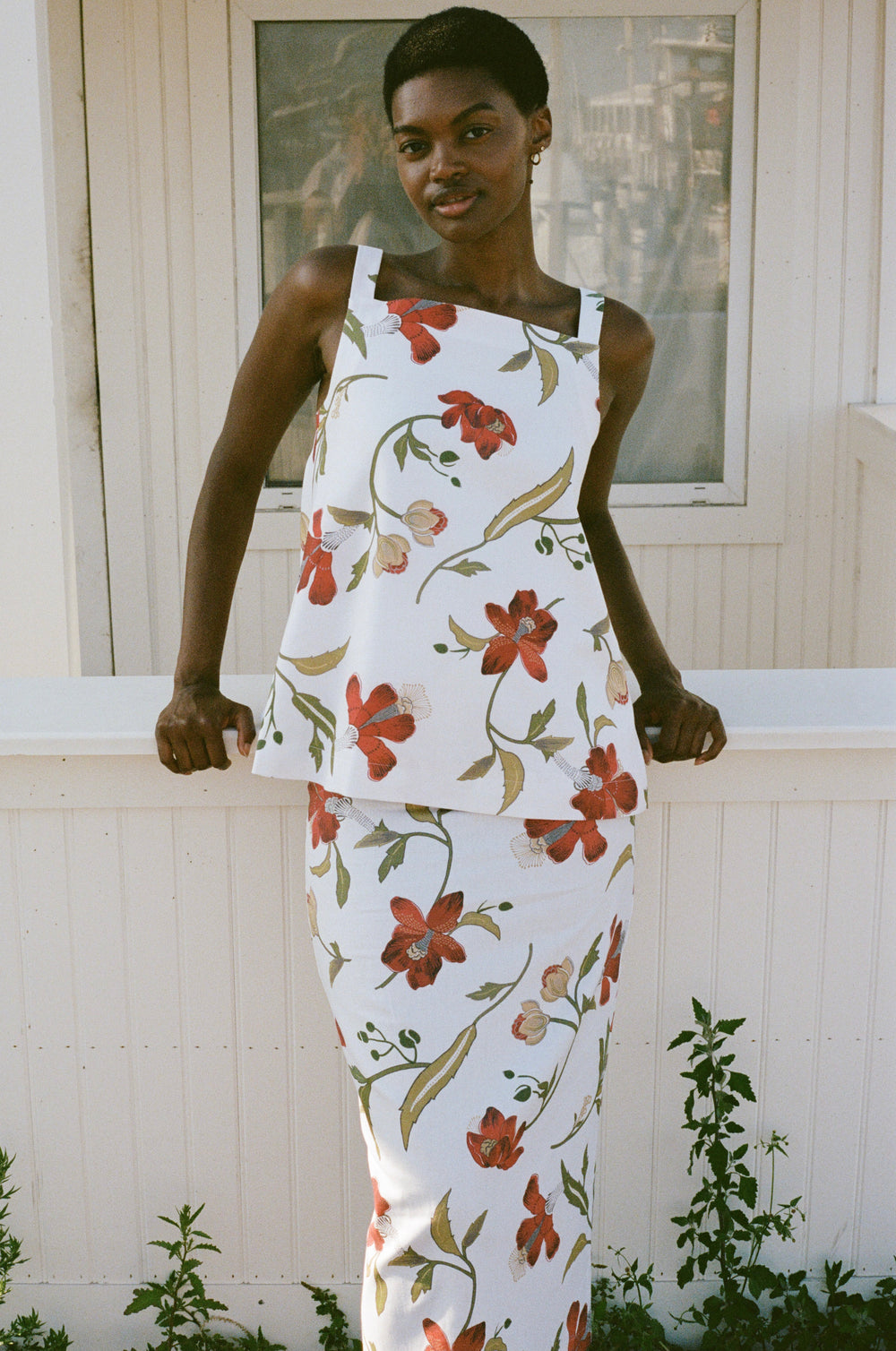 Front view of Pencil Skirt in Red Hibiscus showing high-waisted fitted pencil shape and red floral print on a white porch