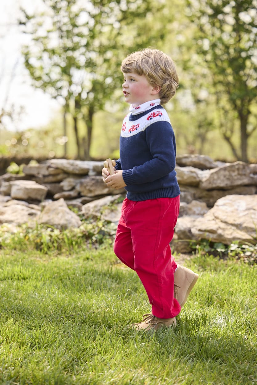 Little English traditional children's clothing. Navy crew neck sweater with red fire truck fair isle detail. Layered over white knit turtleneck with all-over fire truck print. Paired with red corduroy banded pants.  Fall outfit for toddler boys.