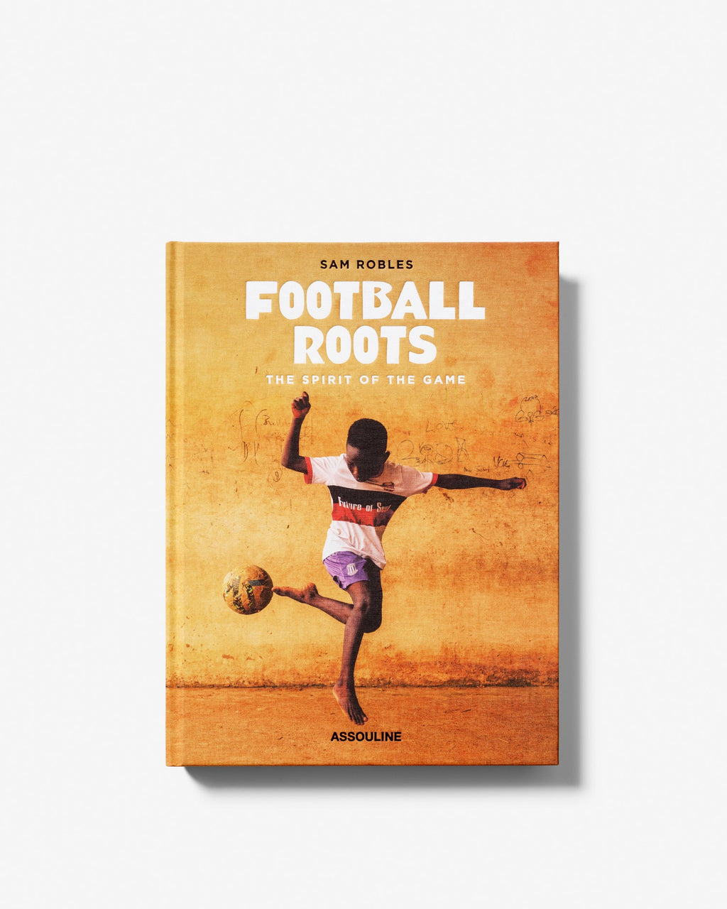 Book cover of 'Football Roots' with a person kicking a soccer ball on a yellow background