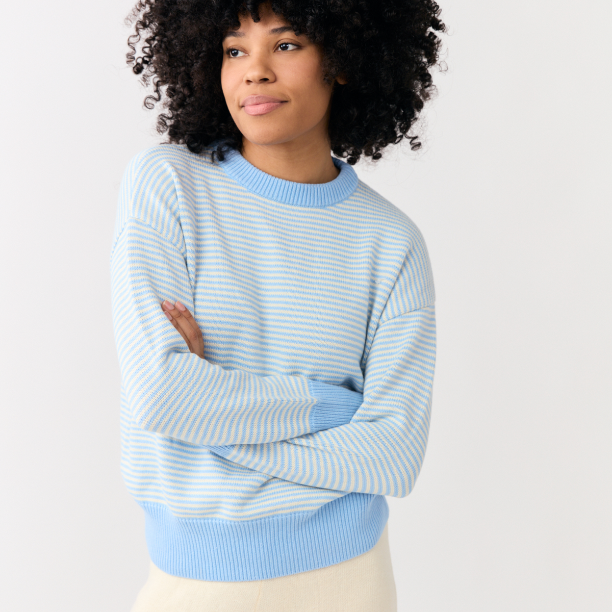 Three-quarter view of Chalet Stripe knit sweater on model, light blue and cream stripes, relaxed fit, dolman sleeves
