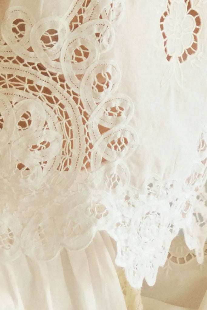 The Francesca Top in white lace has a cropped profile and sleeveless.