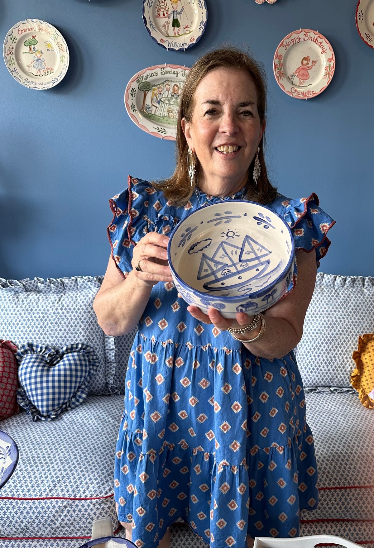 Woman holding a hand-painted blue-and-white Nantucket pet bowl in a coastal-themed room with decorative plates