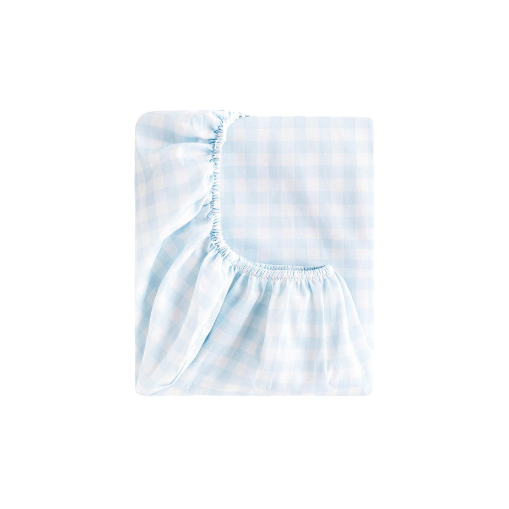 Folded Picnic Gingham crib sheet in blue showing elastic corner on white background