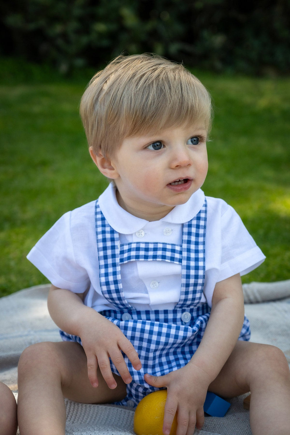 Front view of Leonardo Romper in Midnight Gingham on toddler model showing gingham suspenders, buttons and white collar