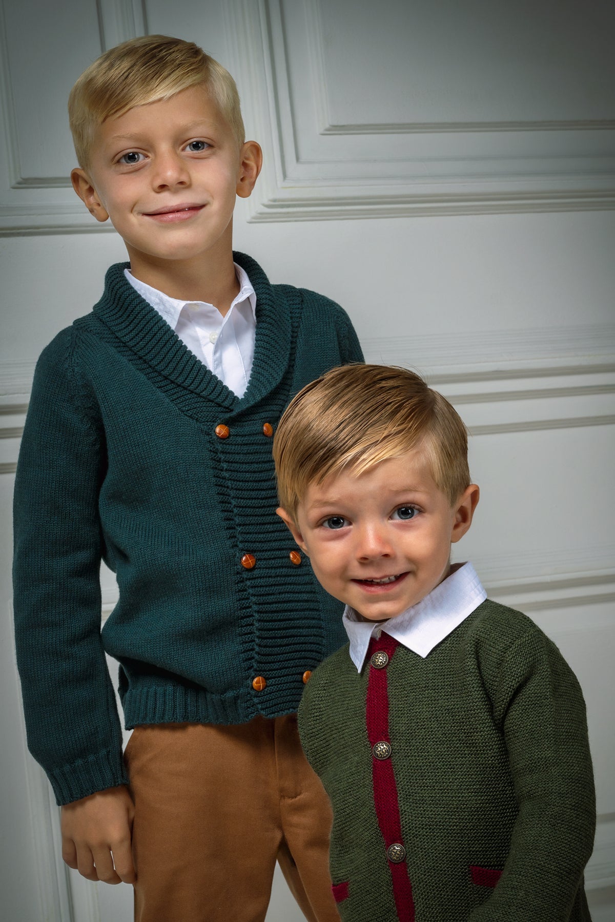 Front view of the Felipe Sweater in Evergreen showcasing a ribbed collar and caramel buttons with children indoors