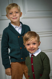 Front view of the Felipe Sweater in Evergreen showcasing a ribbed collar and caramel buttons with children indoors