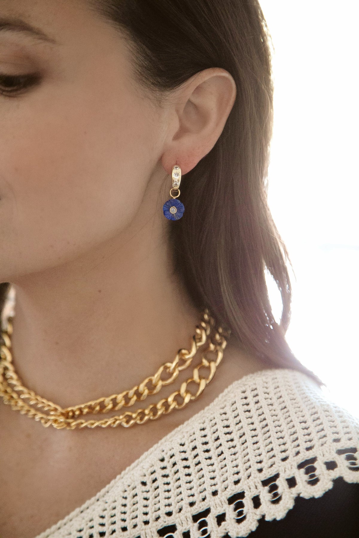 Close-up side view of Garden Party Huggies in lapis showing carved lapis flower drop and 18K gold-plated hoop with crystal accents on model