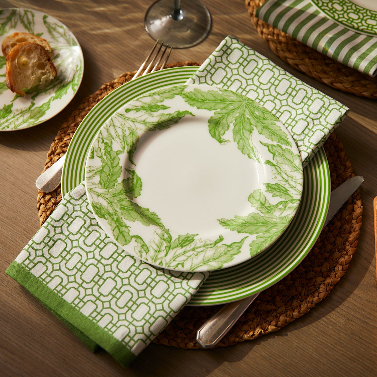 Angled view of Newport Garden Gate Dinner Napkins in Green, set of 4 showcasing geometric pattern on a plated table