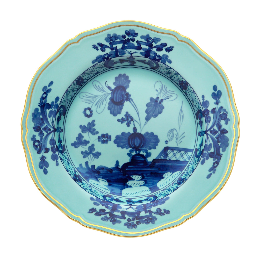 Top-down view of Oriente Italiano charger plate Iris with blue floral motif and gold scalloped rim on white background
