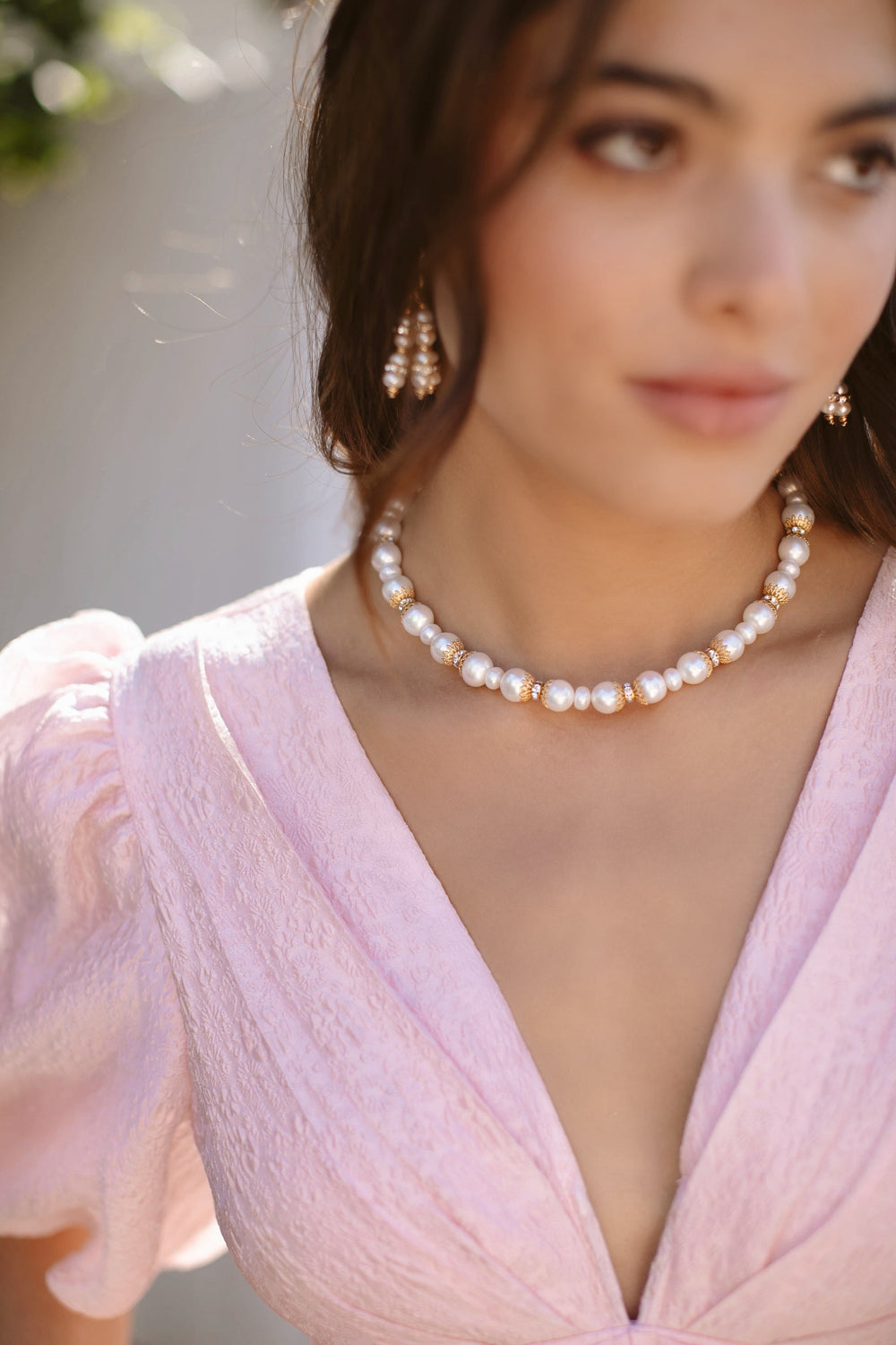 Close up of Gladys Necklace on model showcasing freshwater pearls and 24K gold plated spacers against a pink dress