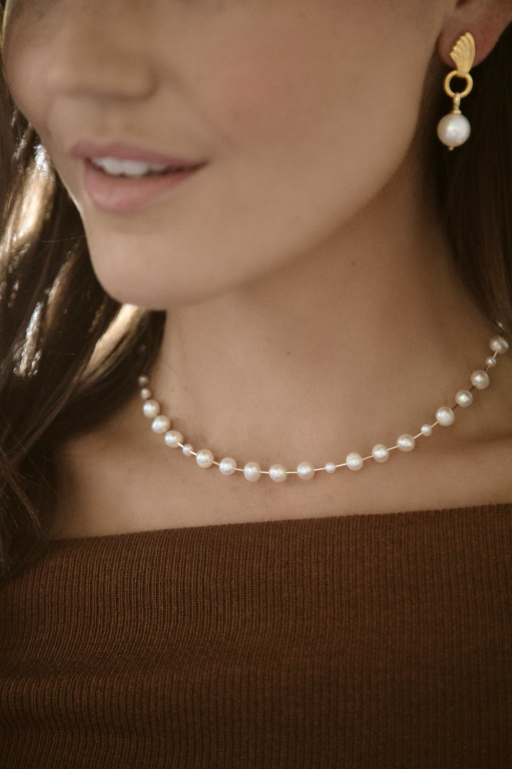 Close-up of Golden Rod Necklace showcasing freshwater pearls on gold-filled bars, worn as a choker against a brown top