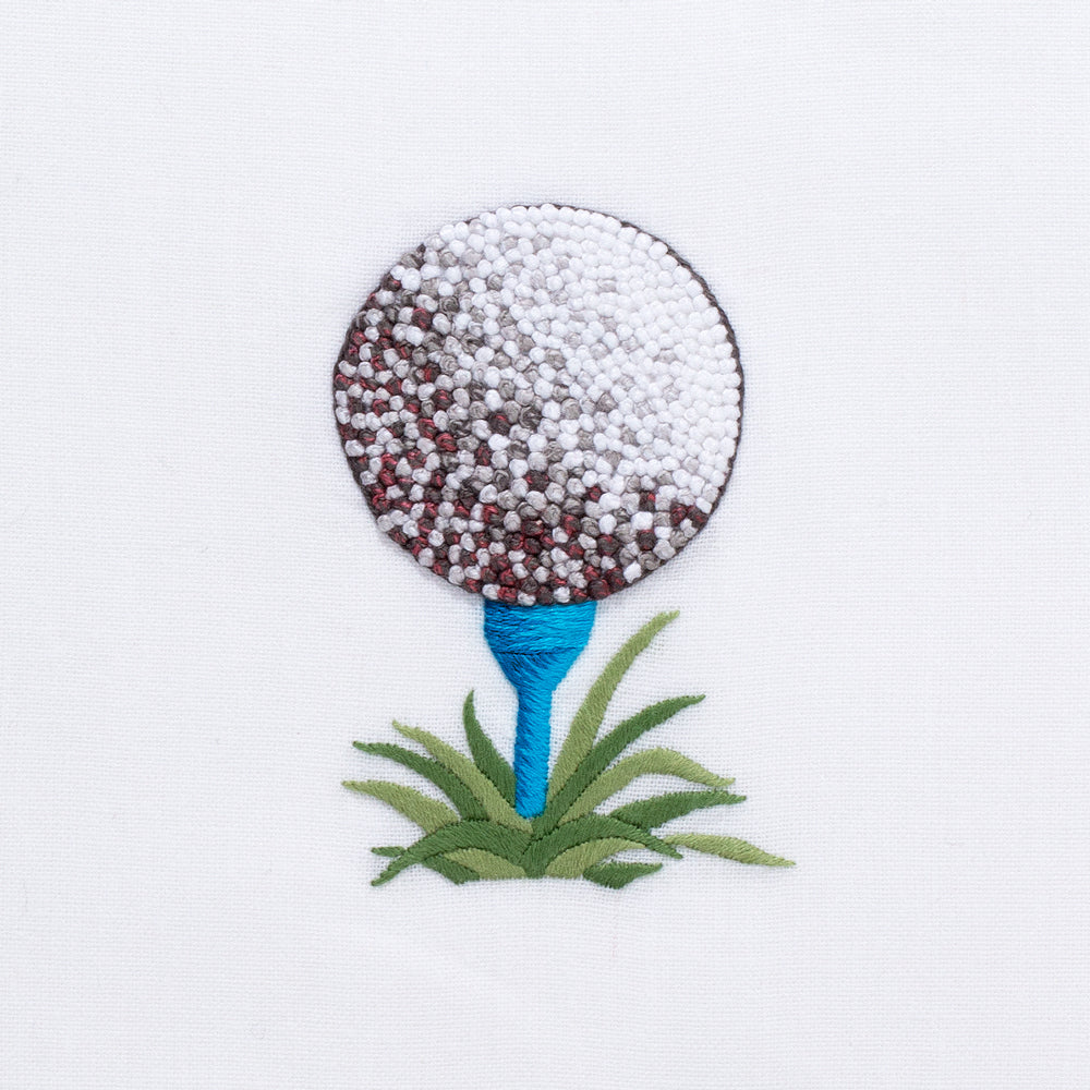 Close-up of Golf Ball Tissue Box Cover showing hand-embroidered golf ball on a blue tee with green grass on white cotton