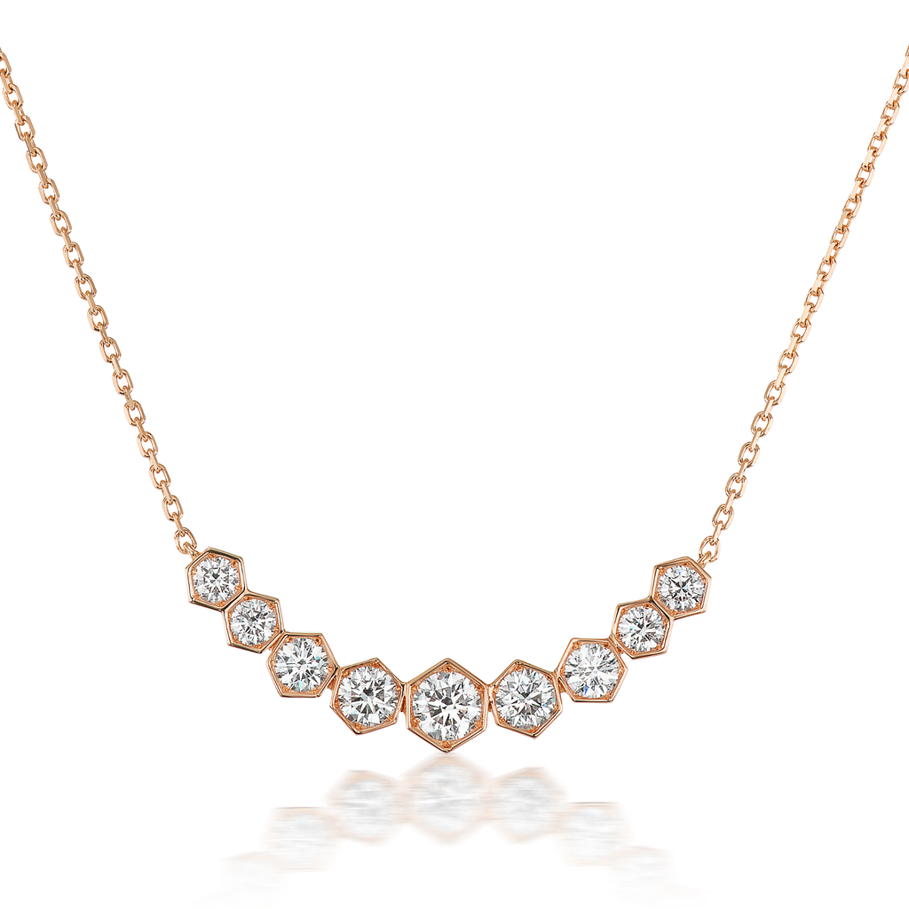 The Bezel Set Hexagon Necklace with Graduated Brilliant Diamonds features eight rose gold 18k hexagon settings, each holding a round diamond, arranged in a gentle curve on a delicate chain.
