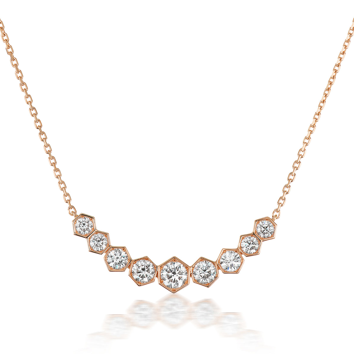 The Bezel Set Hexagon Necklace with Graduated Brilliant Diamonds features eight rose gold 18k hexagon settings, each holding a round diamond, arranged in a gentle curve on a delicate chain.