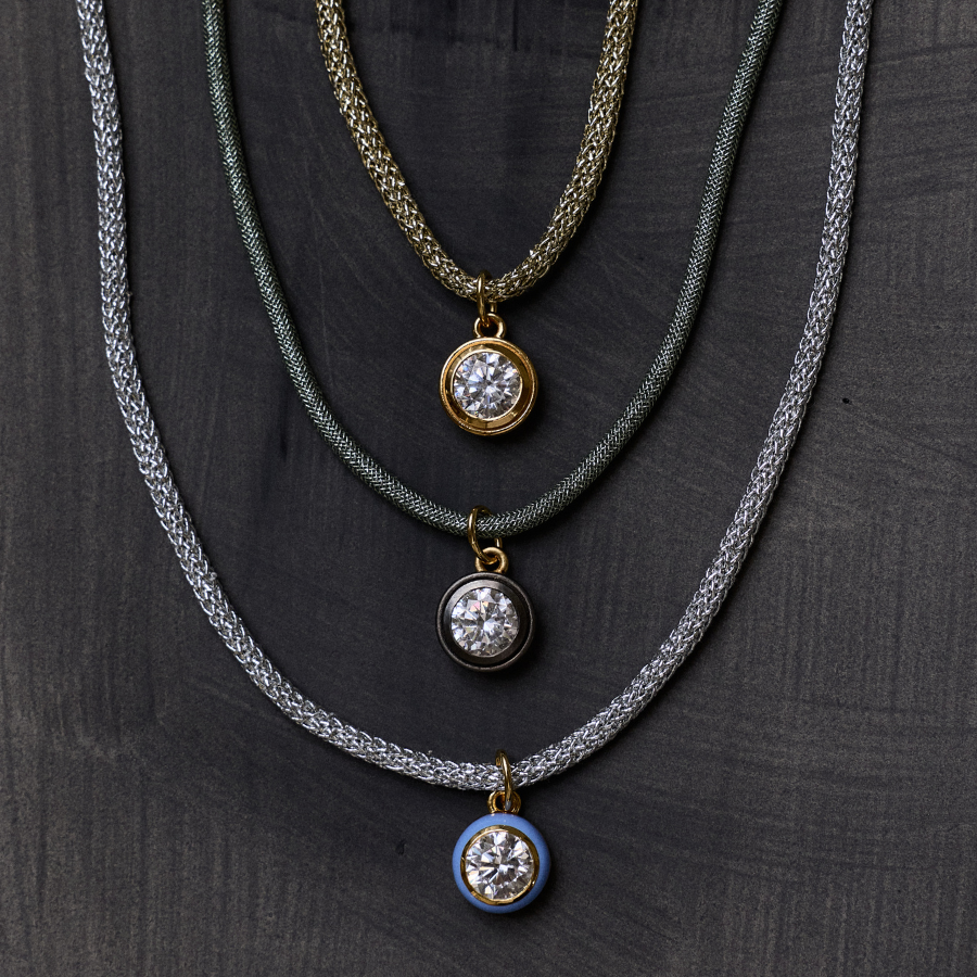 Front view of green Lurex necklace cord with rhodium bezel charm showcasing layered cords on a dark background