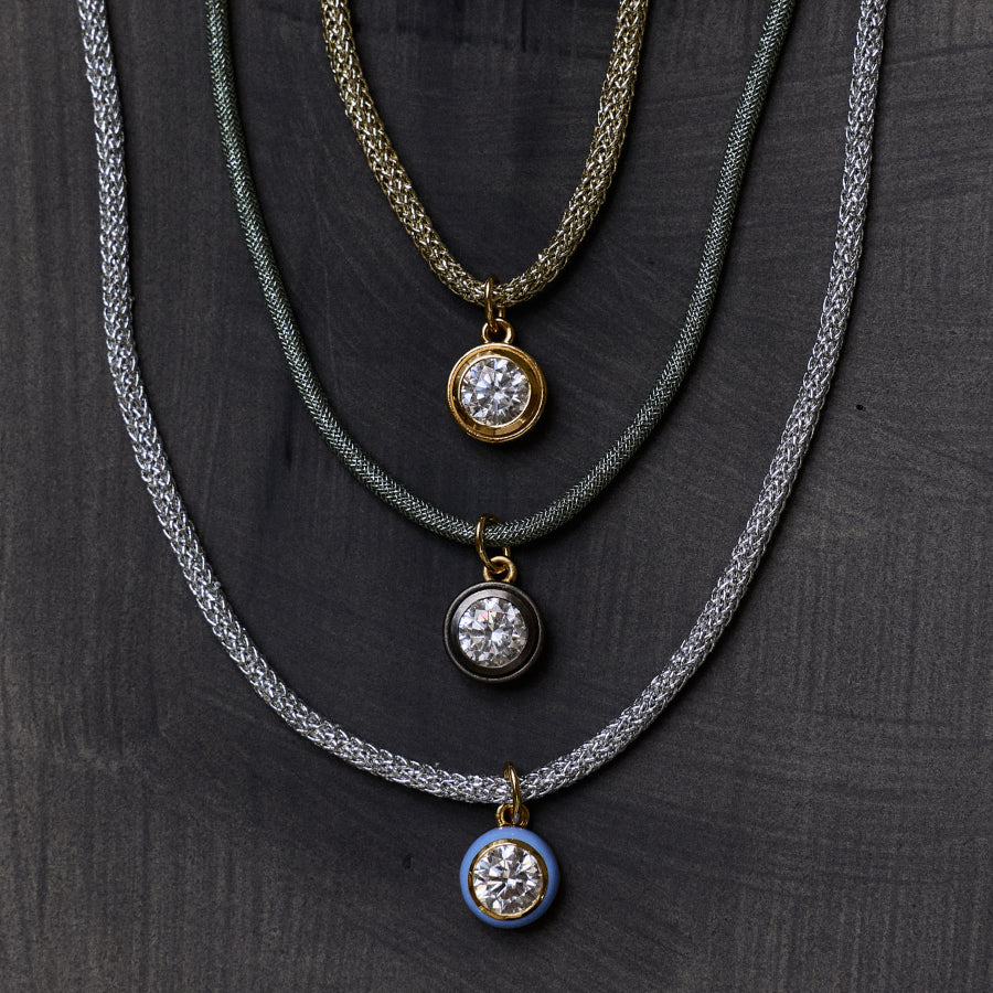 Front view of green Lurex necklace cord with rhodium bezel charm showcasing layered cords on a dark background