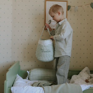 Young boy holding a green gingham quilted basket. 