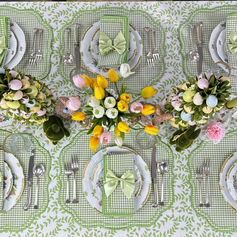 Easter-themed table setting with floral centerpieces, green gingham luxury embroidered placemats and napkins, and decorative herend plates.