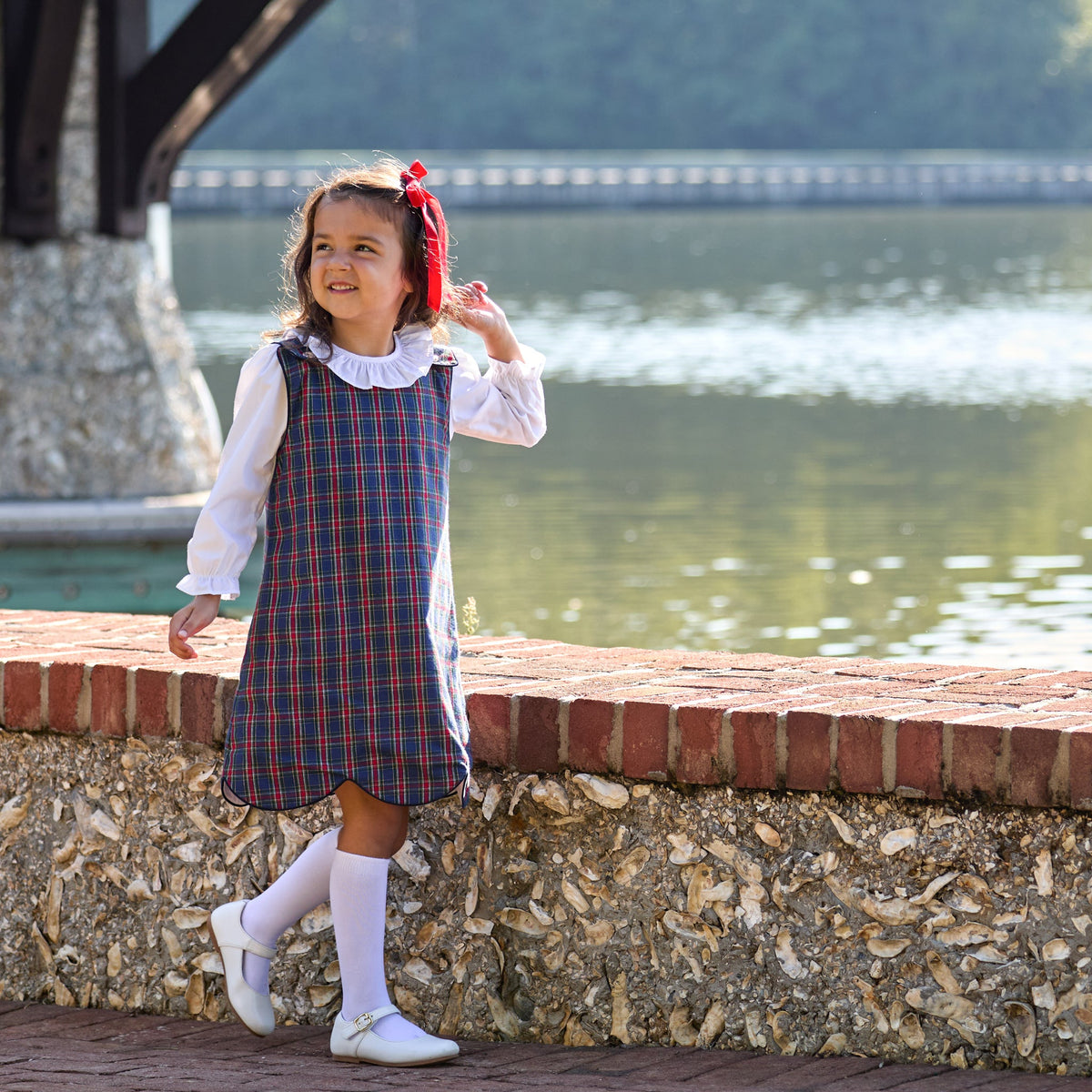 Henry Duvall Janie Jumper girls’ holiday dress in Tinsel Tartan, a navy, red and green plaid with subtle gold metallic thread, scalloped hem, navy piping and gold shoulder buttons.