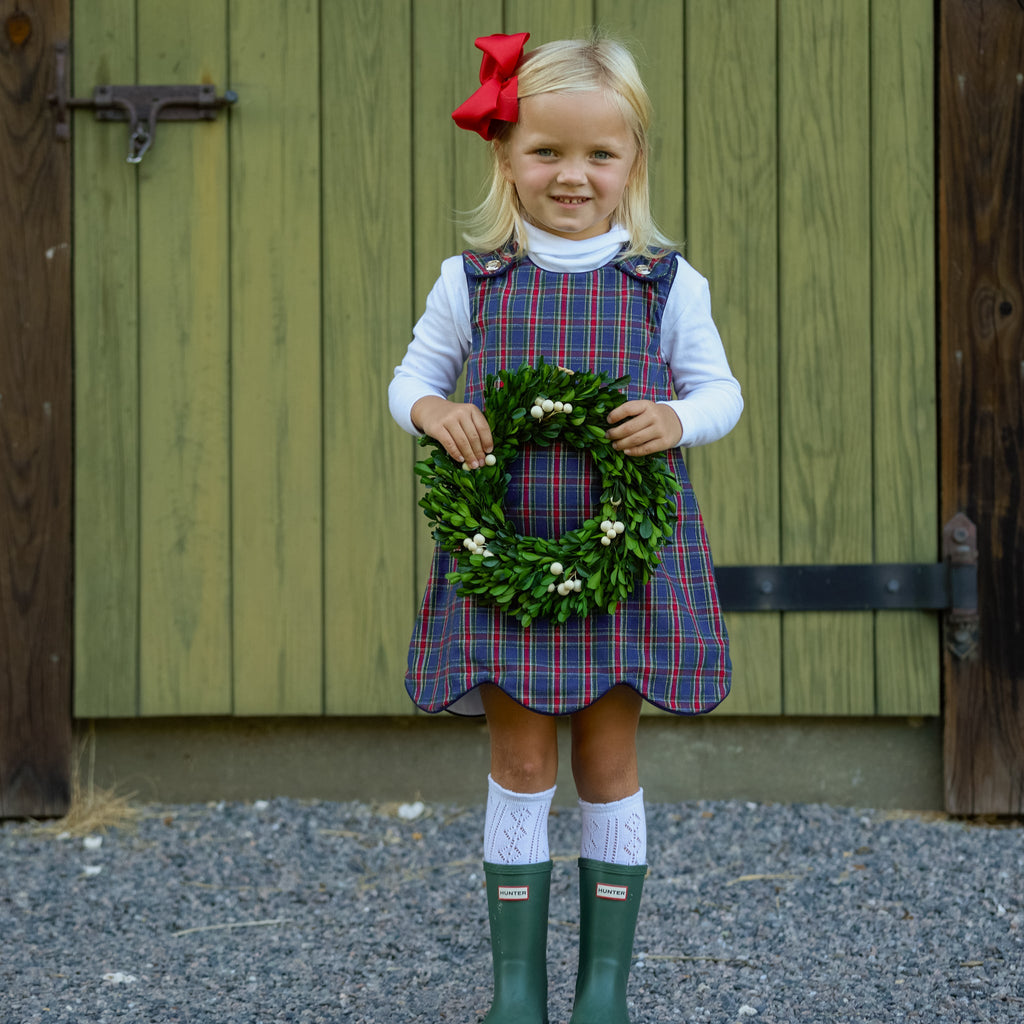 Henry Duvall Janie Jumper girls’ holiday dress in Tinsel Tartan, a navy, red and green plaid with subtle gold metallic thread, scalloped hem, navy piping and gold shoulder buttons.