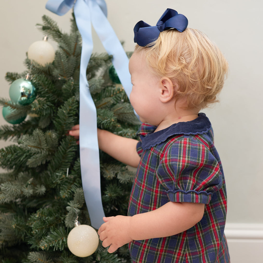 Child wearing the Beatrice Bubble in Tinsel Tartan while decorating a Christmas tree