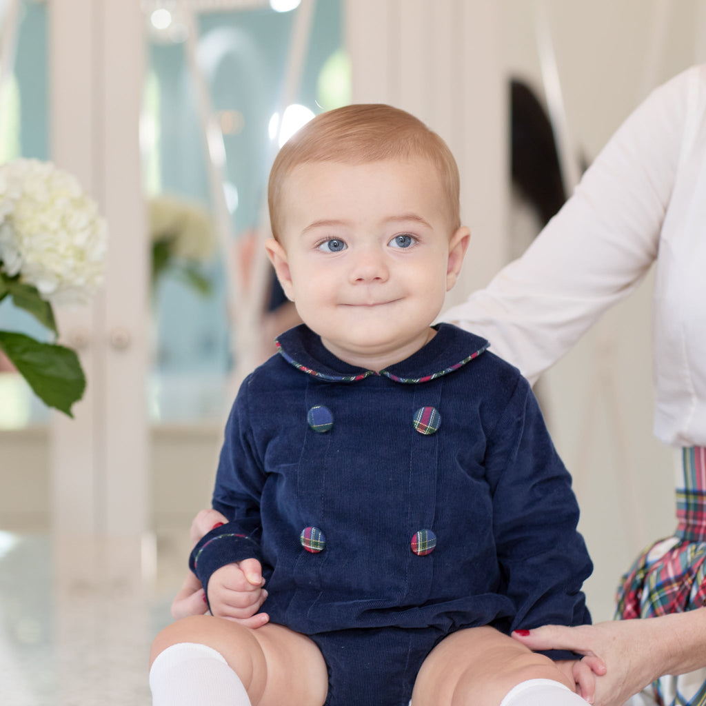 Baby boys’ Banks Bubble in Midnight Blue Corduroy with Tinsel Tartan-covered buttons and coordinating plaid trim at the Peter Pan collar and cuffs.