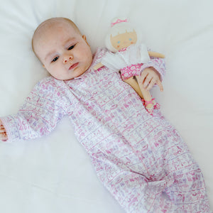Top view of pink Ballet Snap Baby Onesie showcasing an allover ballet print on a baby lying on white bedding