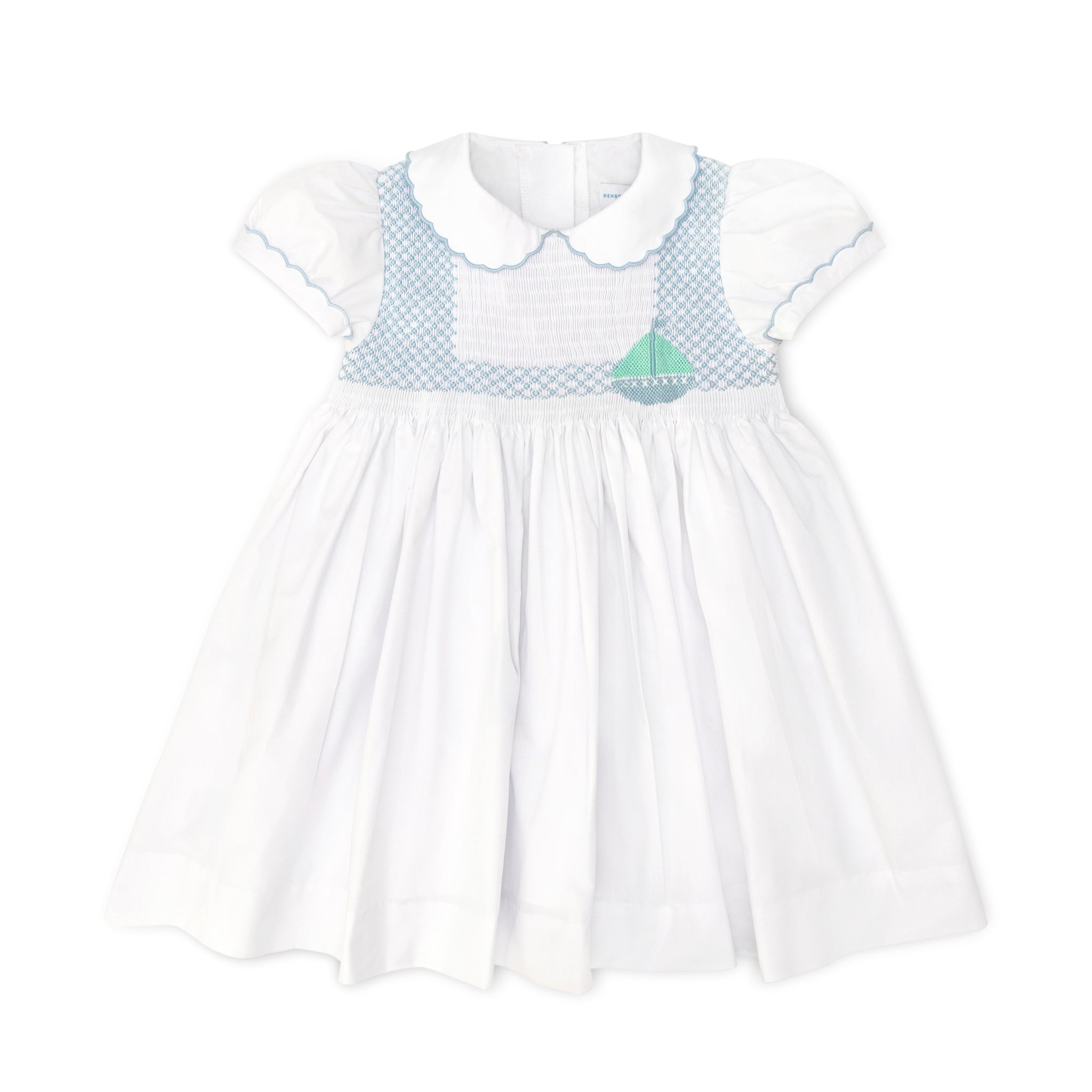 Henry Duvall Eloise Dress in white cotton with Bailey’s Bay Blue trim and hand-smocked sailboats, classic heirloom baby girl summer outfit with scalloped Peter Pan collar