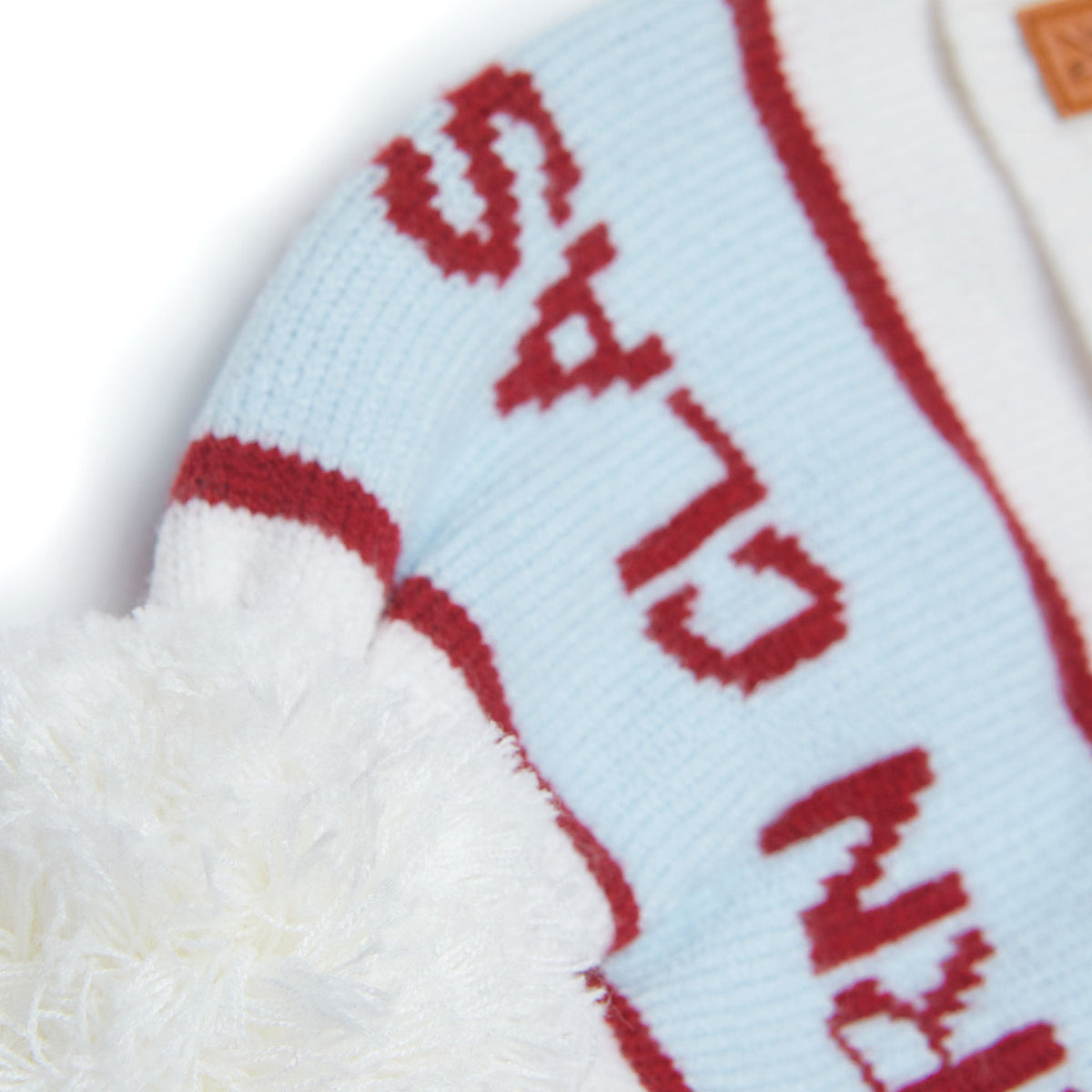 Close-up of Northern Classics Knit Pom Hat in Winter White and Cloud Blue showcasing oversized pom and red knit pattern