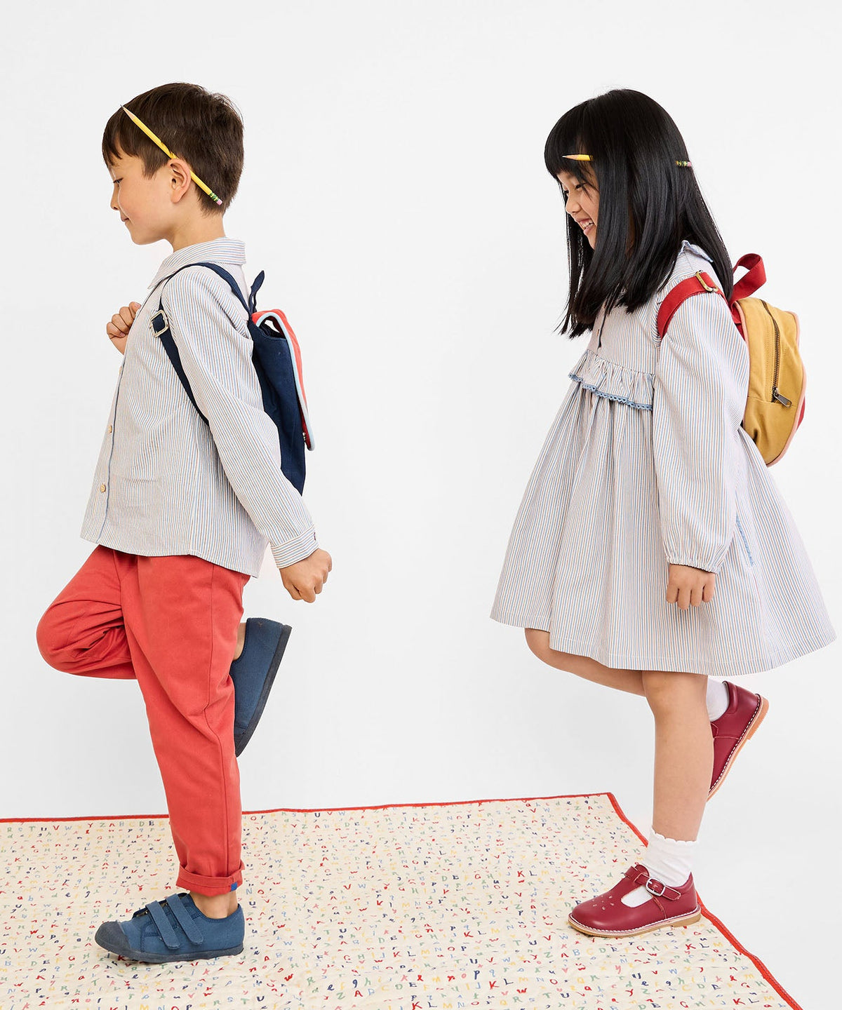 Side view of Hannah Dress in Indigo Linen Stripe showcasing ruffled collar and lace trim on child against white background