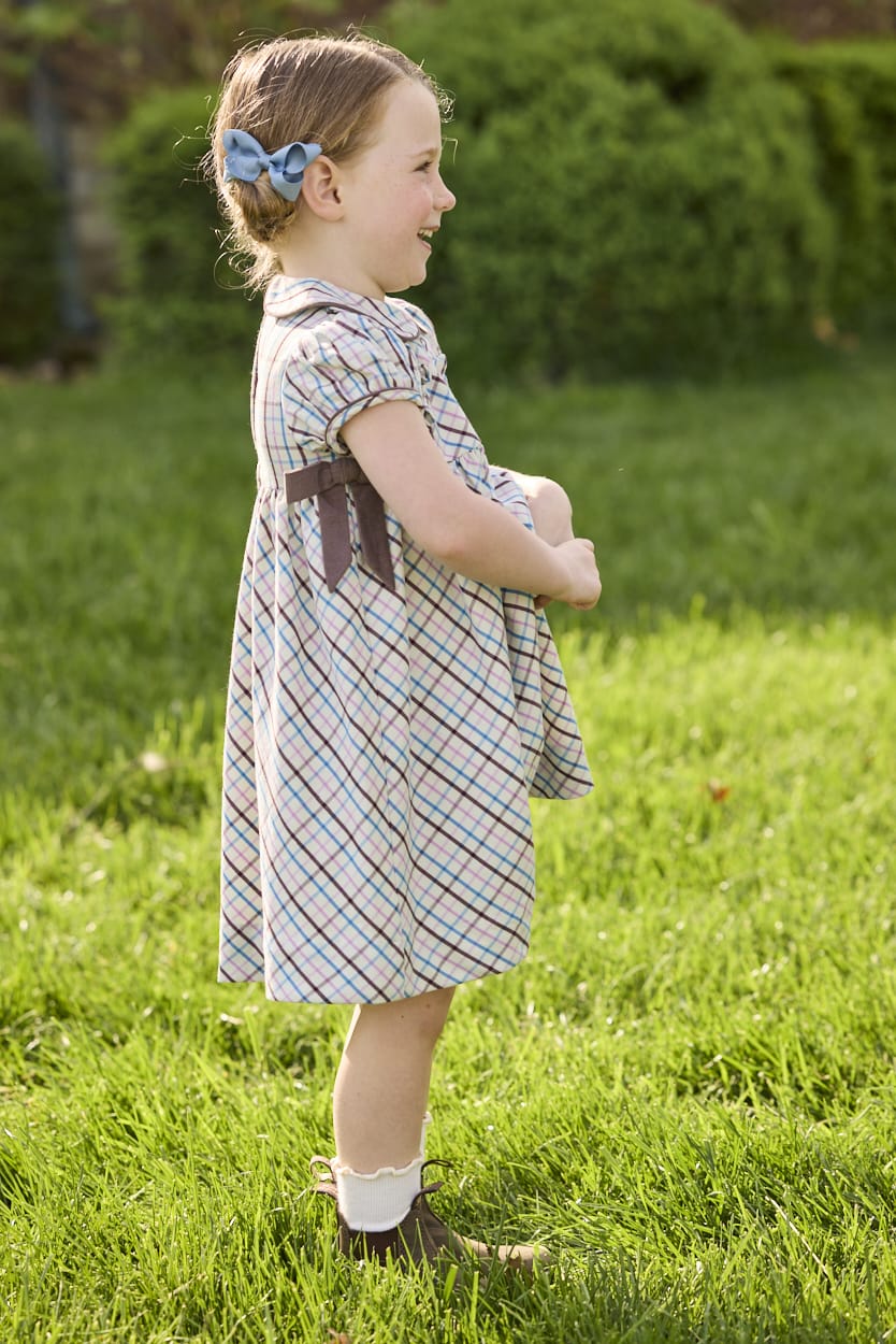 Little English traditional children's clothing. Short sleeve peter pan dress in blue, pink, and brown Wilmington Plaid with brown corduroy piping and bow details for little girls.