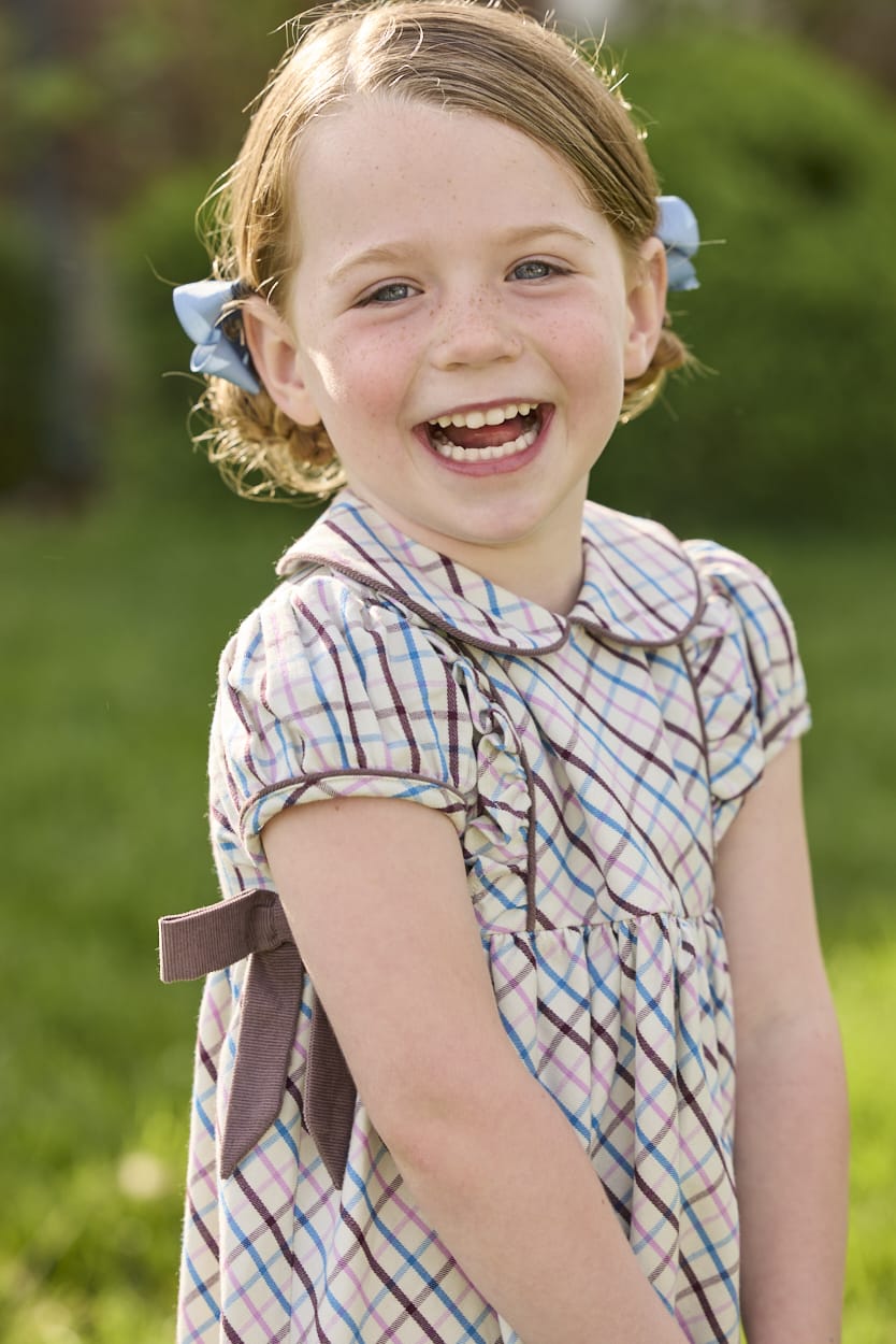 Little English traditional children's clothing. Short sleeve peter pan dress in blue, pink, and brown Wilmington Plaid with brown corduroy piping and bow details for little girls.