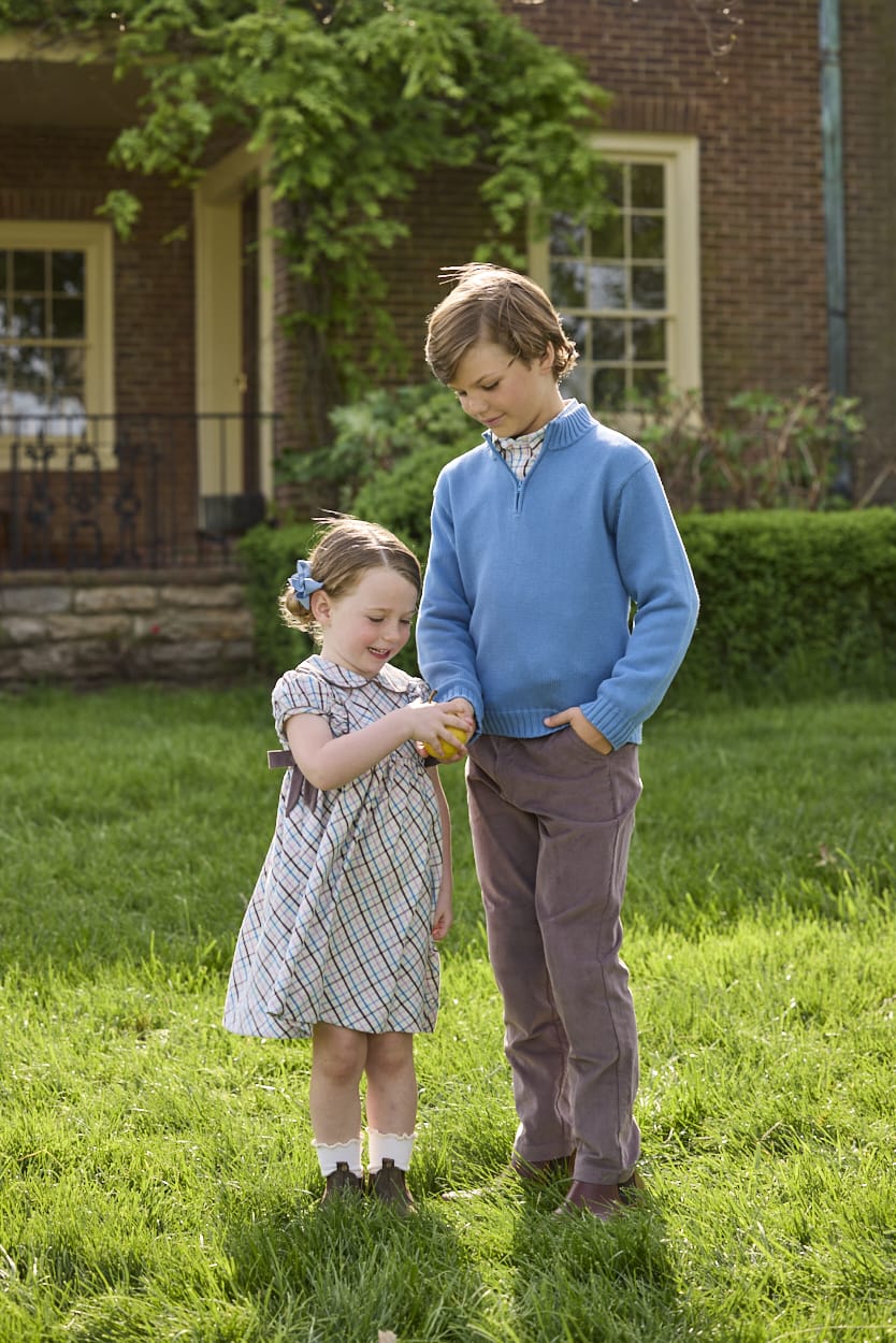 Little English traditional children's clothing. Boys stormy blue quarter zip sweater layered over blue, pink, and brown Wilmington Plaid button down shirt and paired with chocolate brown corduroy classic pants.  Short sleeve peter pan dress in blue, pink, and brown Wilmington Plaid with brown corduroy details for little girls.