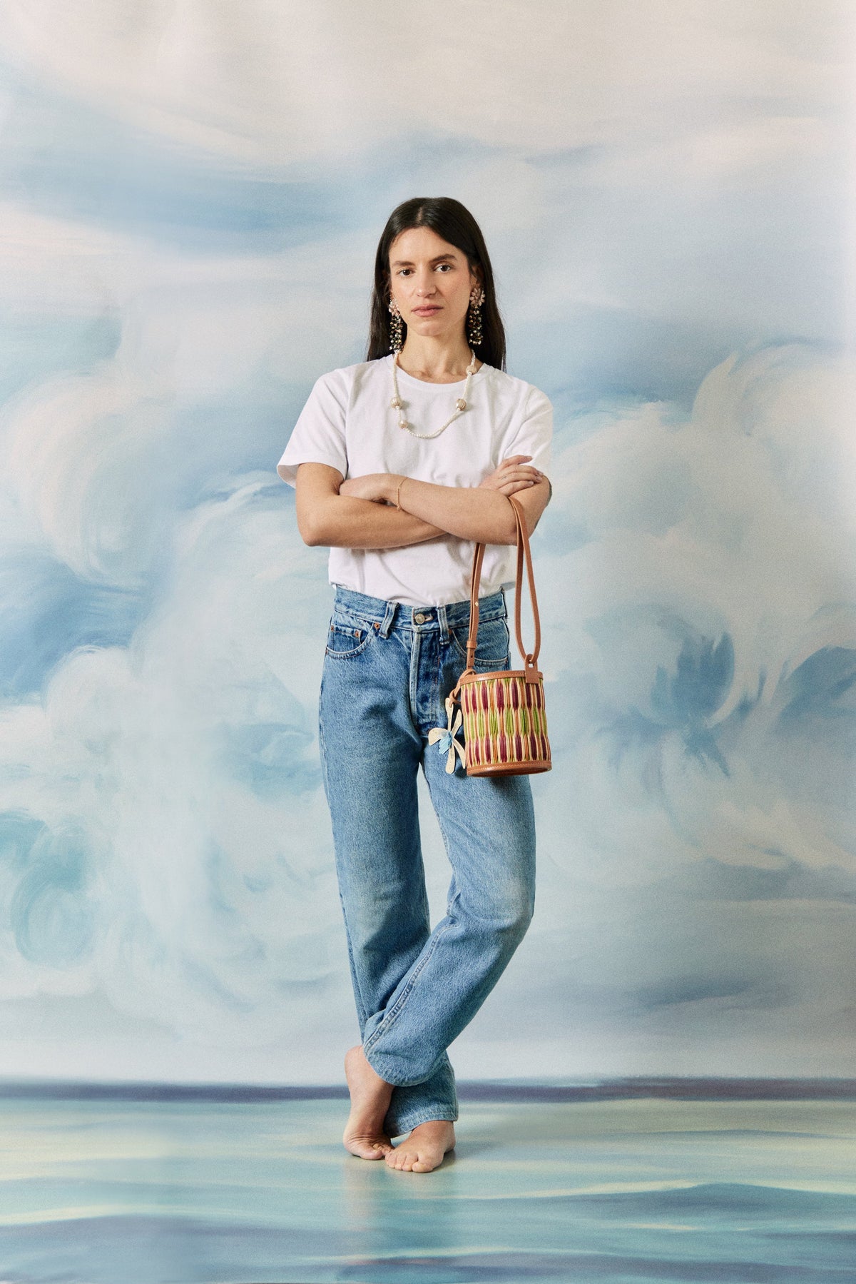 Front view of Cupid Madras bucket bag in lime with woven reed body, leather trim, adjustable strap and twill drawstring pouch