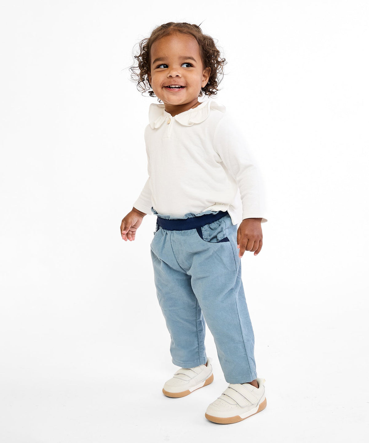 Three-quarter view of Hen Baby Shirt in Vanilla Piping showing ruffle collar, long sleeves on toddler against white background
