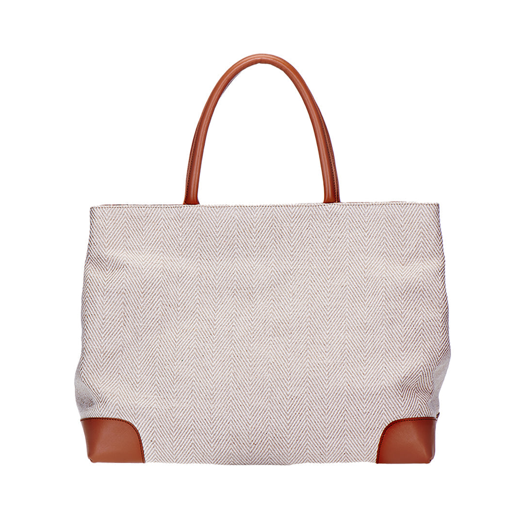 Front view of Cream Herringbone Tote showcasing herringbone fabric with brown leather handles and corner accents on white background