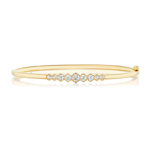 The Graduated Hexagon Bezel Set Diamond Bangle in 18k gold features a row of round white diamonds in graduated sizes set across the top, shown on a white background.