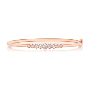 The Graduated Hexagon Bezel Set Diamond Bangle features round white diamonds in graduated sizes, set in 18k rose gold with a sleek, polished finish and minimalist, elegant style.