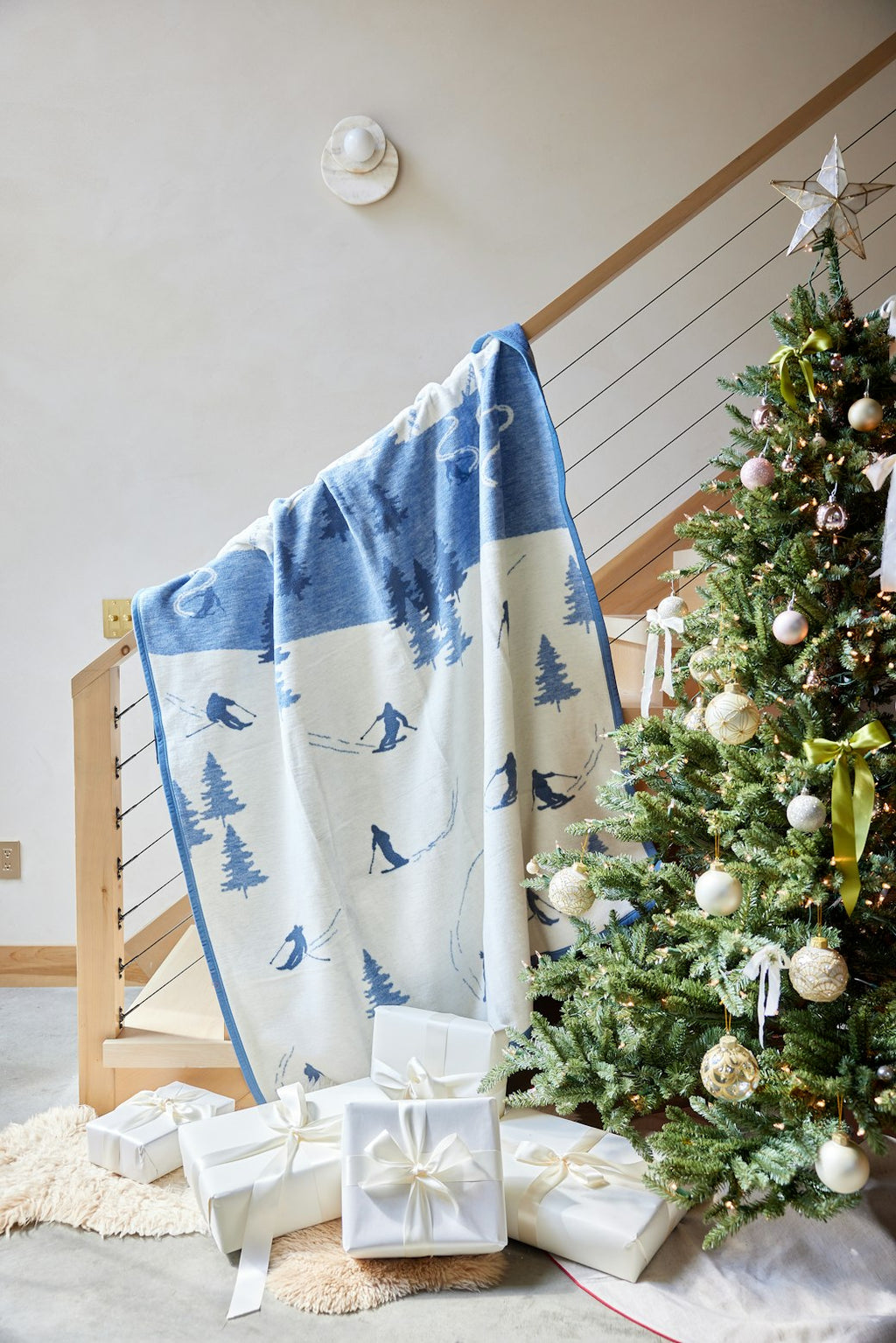 Blue and cream blanket with ski and tree pattern draped over wooden railing.