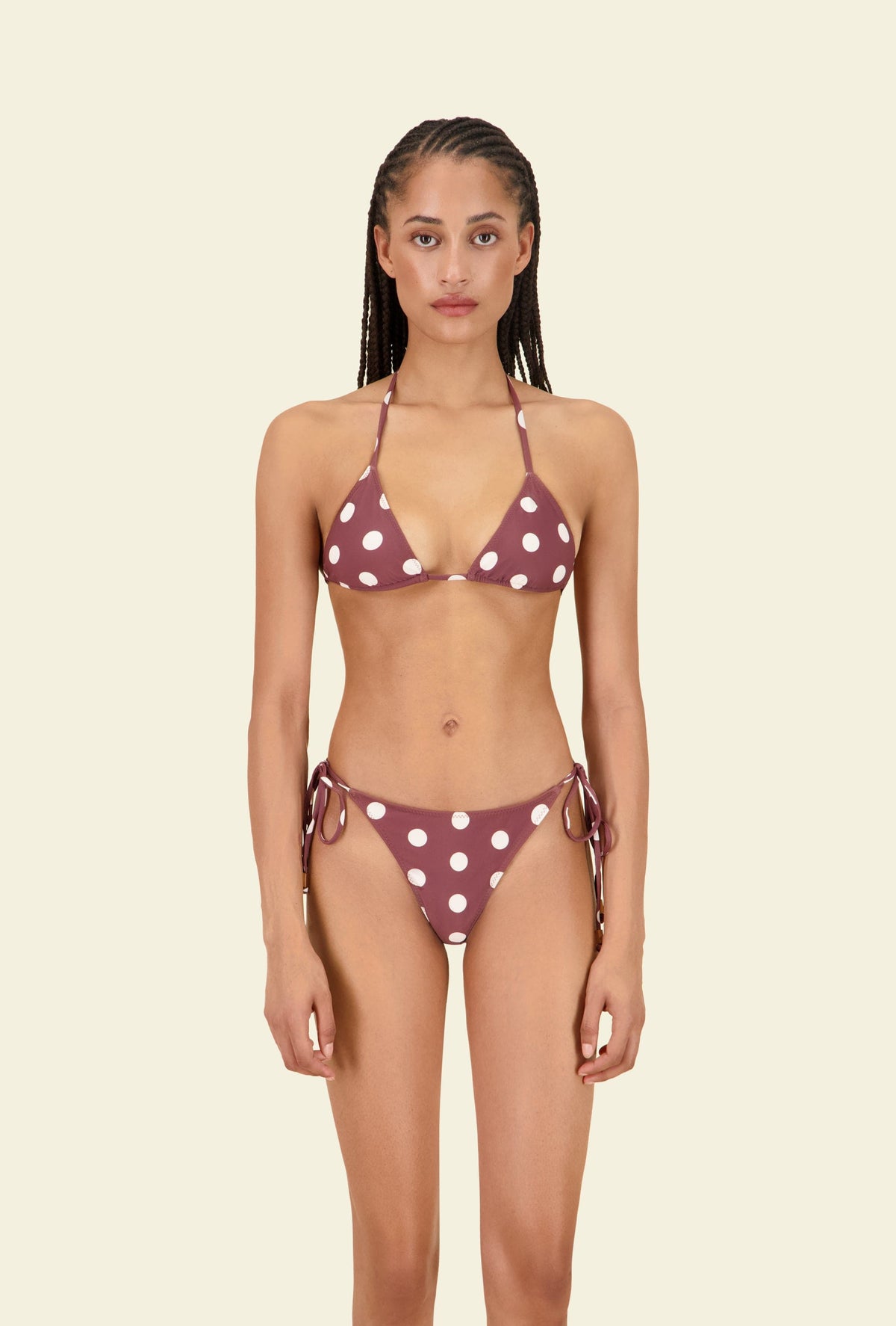 Front view of The Nat Bottom tie-side bikini bottom in mauve with white polka dots, showing moderate coverage and side ties on beige background