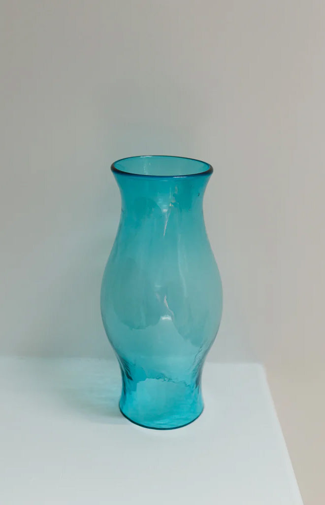 Front view of Hurricane glass vase in aqua showcasing bulbous silhouette and flared opening on plain light background