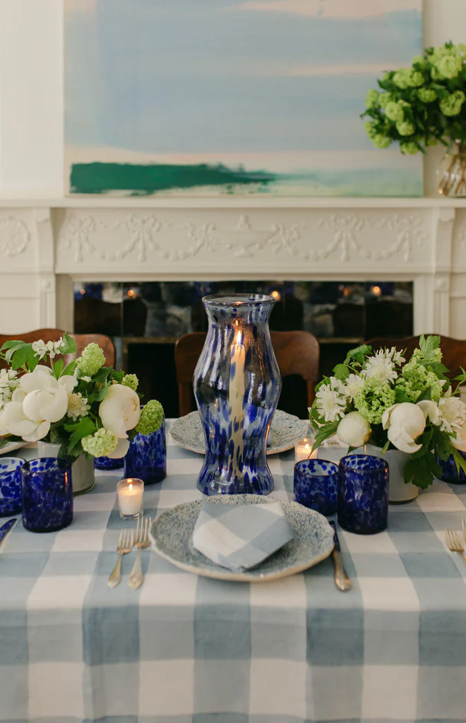 Front view of Hurricane blue marble glass vase showcasing swirled marbling with lit candle on a blue checkered table