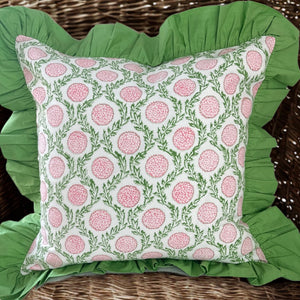 Decorative pillow with pink floral pattern with a green ruffle on wicker chair